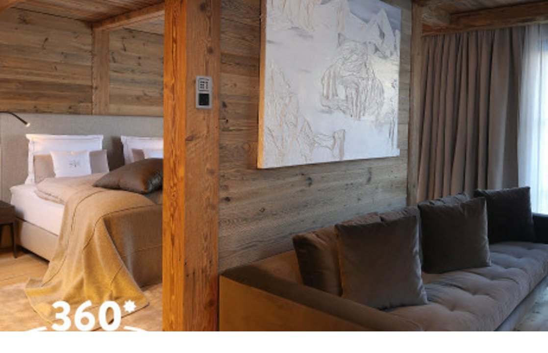 Luxuriöses Hotelzimmer mit Holzverkleidung, gemütlichem Bett, Sofa und großem Fenster im Severin*s The Alpine Retreat, Lech.