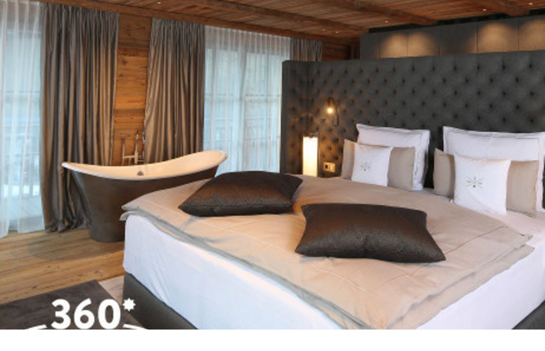 Luxuriöses Hotelzimmer mit großem Bett, freistehender Badewanne und Holzdekor im Severin*s The Alpine Retreat, Lech.