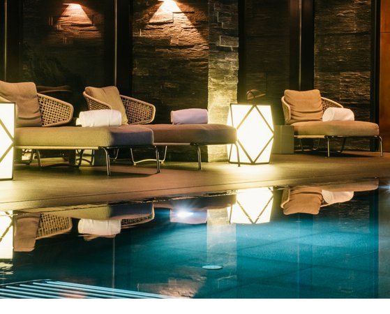 Severin*s Innenpool mit Gegenströmung und Wasserfall Luxuriöser Spa-Bereich mit Liegen, weichem Licht und Pool im Severin*s The Alpine Retreat, Lech.
