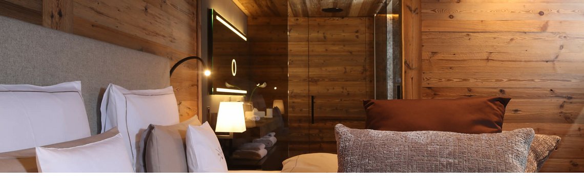 Gemütliches Schlafzimmer mit Holzwänden, eleganten Kissen und sanfter Beleuchtung im Hotel Severin*s The Alpine Retreat.