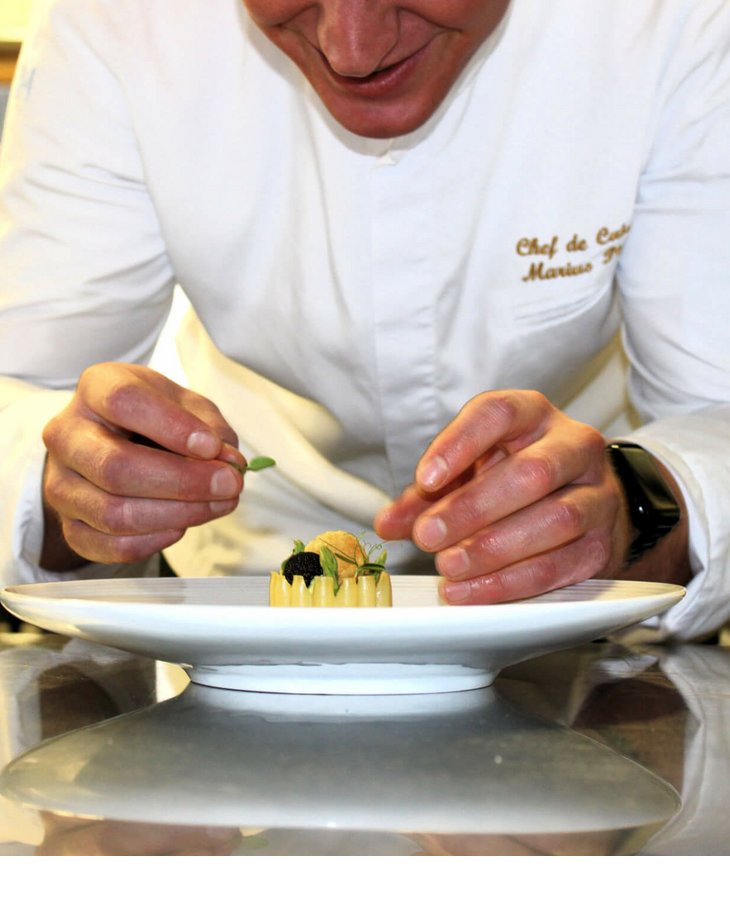Ein Koch verziert ein Gourmetgericht in der Küche des Severin*s The Alpine Retreat in Lech.