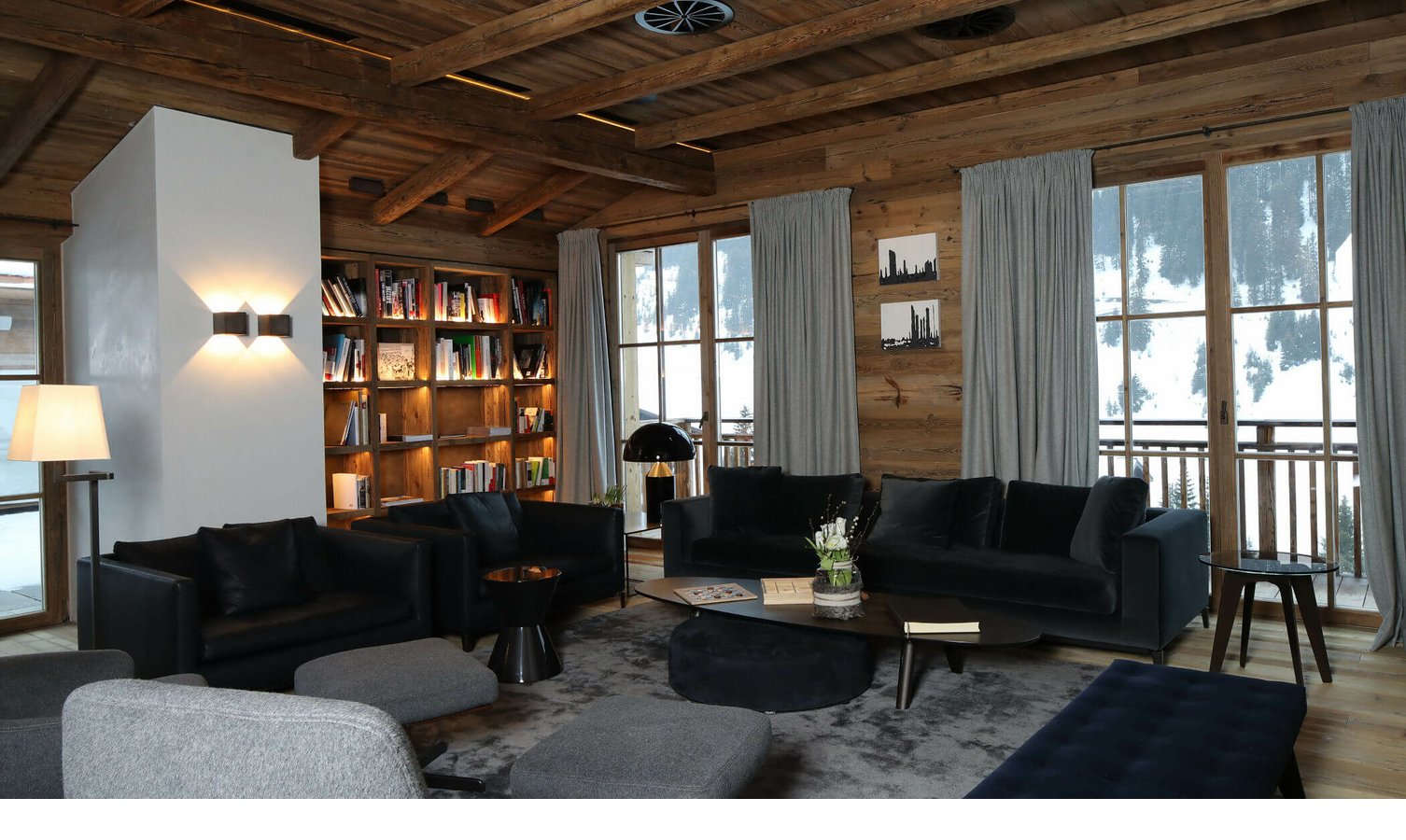 Gemütliche Lounge im Hotel Severin*s mit Holzwänden, Bücherregal, Sofas und großem Fenster mit Bergblick.