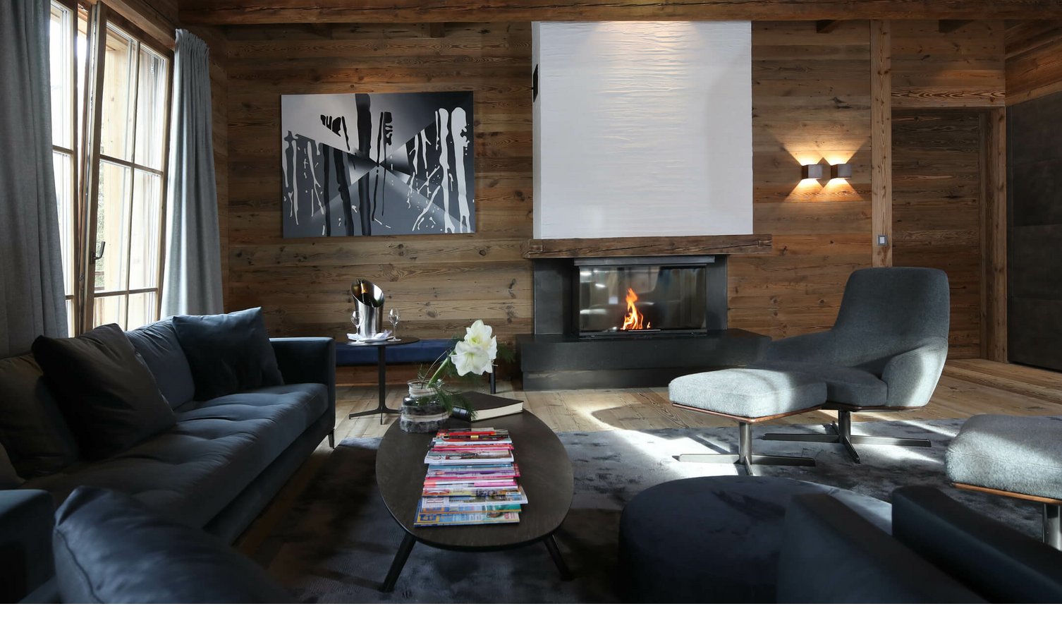Hotelbar im Severin*s - The Alpine Retreat Gemütliches Wohnzimmer mit Kamin, moderner Kunst, blauen Sofas und Holzwänden im Hotel Severin*s The Alpine Retreat.