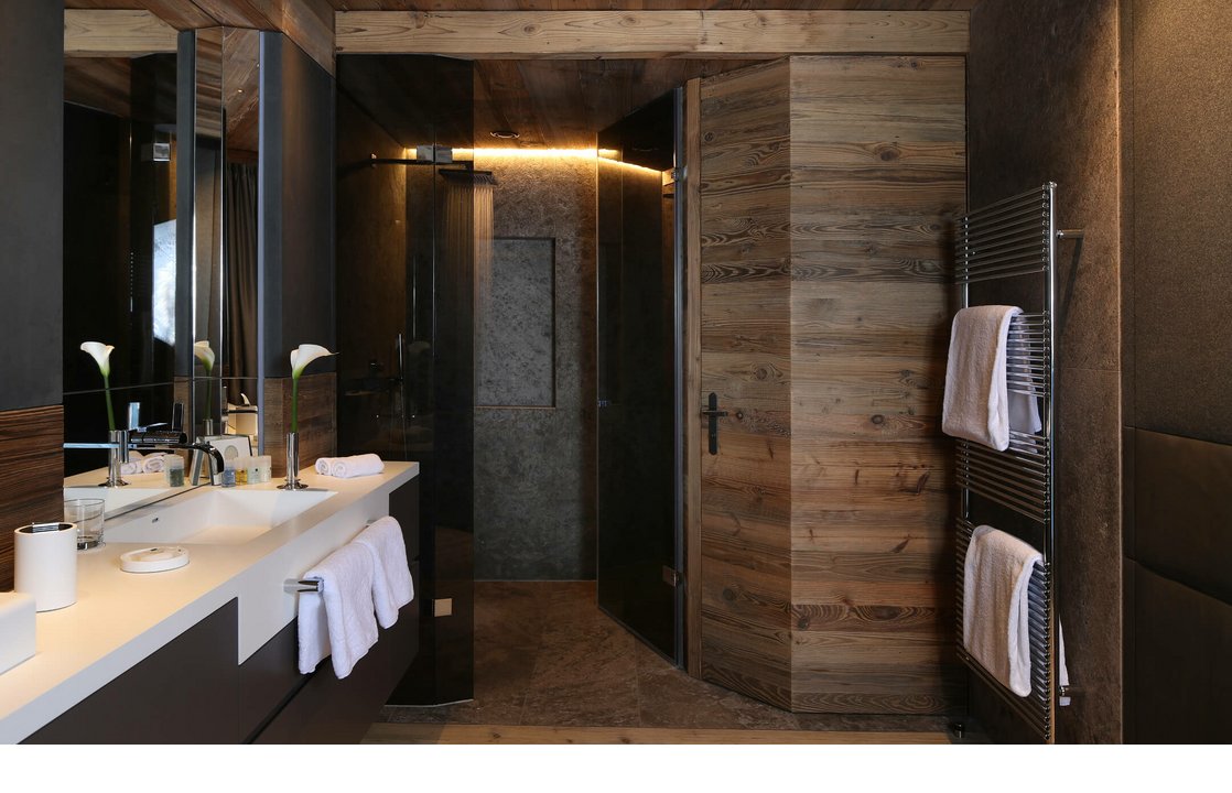 Modernes Badezimmer mit Holzverkleidung, Doppelwaschbecken, Handtüchern und Glasdusche im Severin*s The Alpine Retreat.