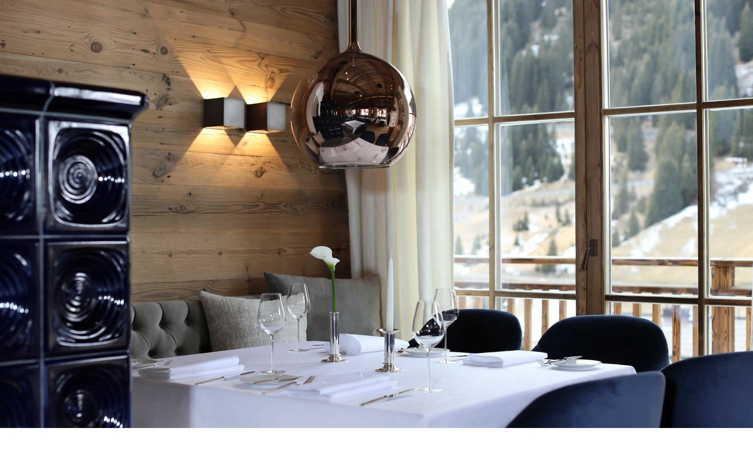 Restaurant im Severin*s in Lech Elegantes Restaurant mit Holzwänden, gedecktem Tisch, großer Fensterfront und Bergblick im Hotel Severin*s The Alpine Retreat.