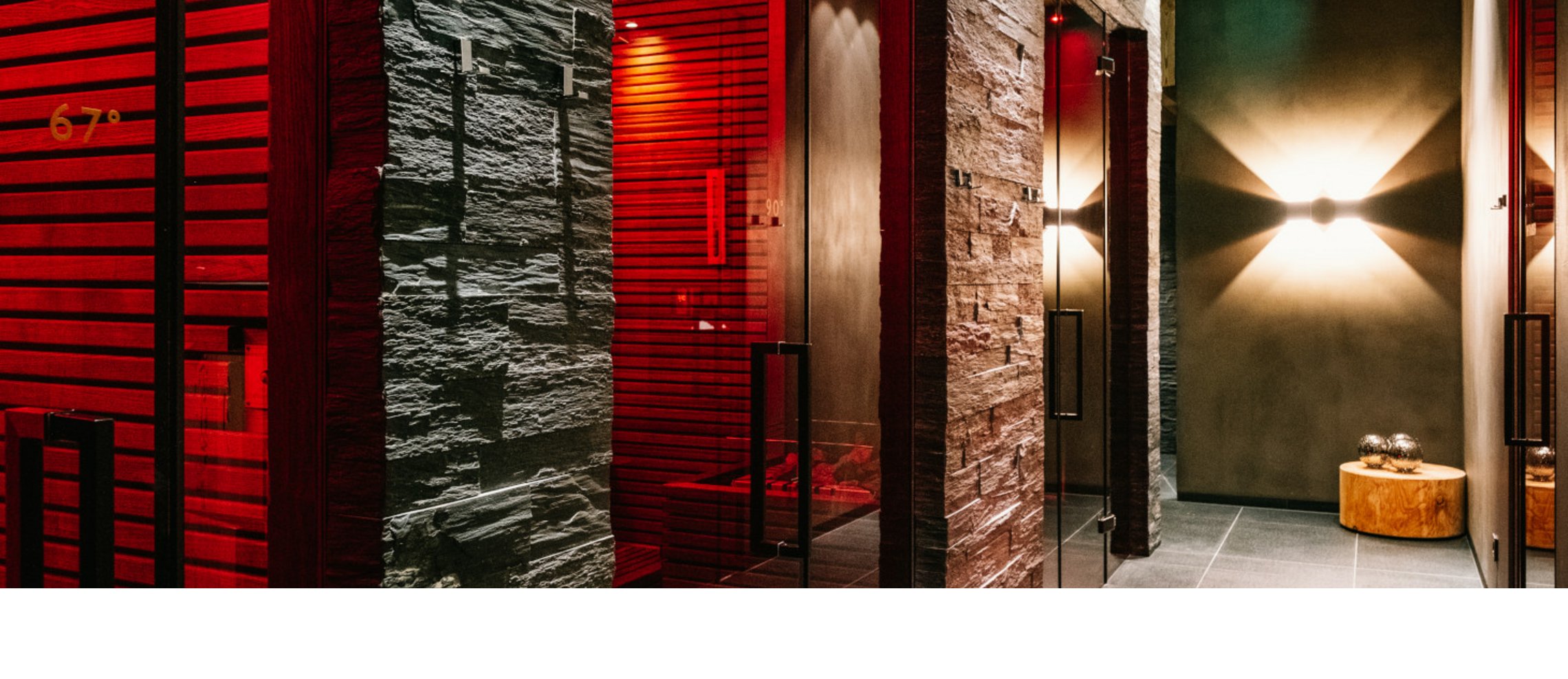 Flur mit moderner Beleuchtung, Steinwänden und Glastüren, die zu Saunen im Hotel Severin*s The Alpine Retreat führen.