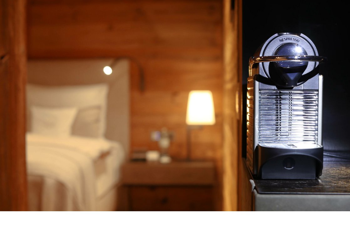 Moderne Kaffeemaschine in einem stilvollen, holzgetäfelten Hotelzimmer mit gemütlicher Beleuchtung.