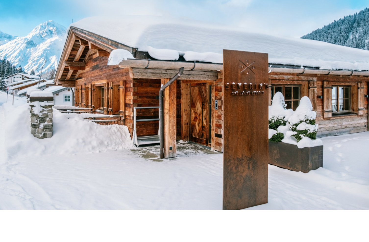 Holzhütte des Severin*s The Alpine Retreat, umgeben von Schnee, mit Bergkulisse im Hintergrund.