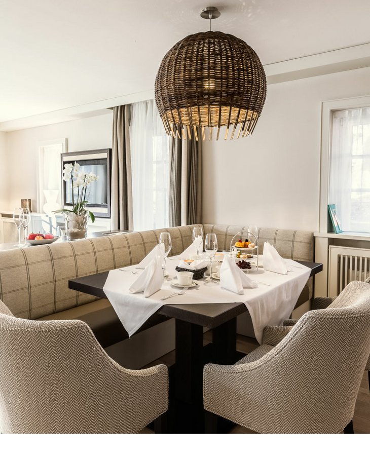 Eleganter Essbereich im Severin*s Resort & Spa mit gedecktem Tisch, gemütlichen Sesseln und hängender Korblampe.