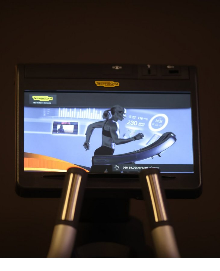 Fitnessbereich Severin*s - The Alpine Retrea Bildschirm eines Fitnessgeräts mit laufender Frau und Trainingsdatenanzeige im Hotel Severin*s The Alpine Retreat.