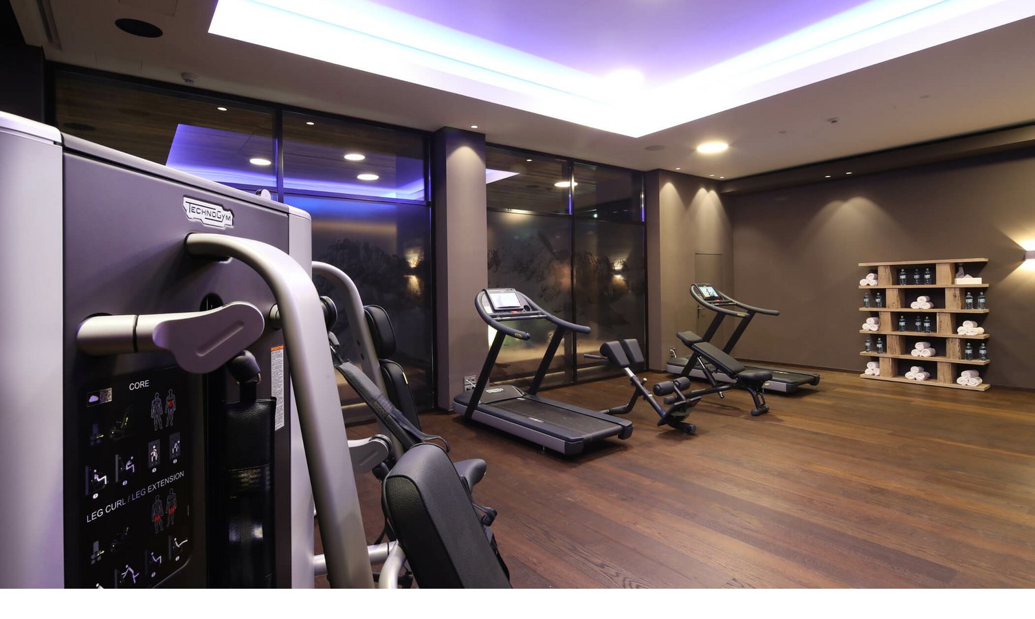 Moderner Fitnessraum im Hotel Severin*s Lech mit Laufbändern, Kraftgeräten und Handtuchregal in stilvollem Ambiente.