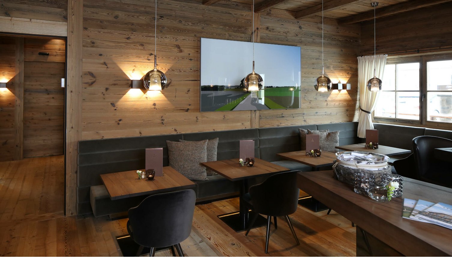 Gemütlicher Essbereich im Hotel Severin*s mit Holzwänden, modernen Lampen und stilvollen Sitzmöbeln.