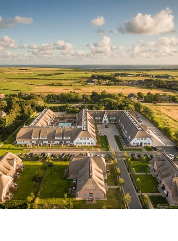 Luftaufnahme des Severin*s Resort & Spa auf Sylt, umgeben von grünen Feldern und idyllischer Landschaft.