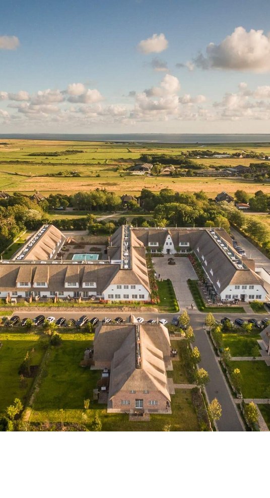 Luftaufnahme des Severin*s Resort & Spa auf Sylt, umgeben von grünen Feldern und idyllischer Landschaft.