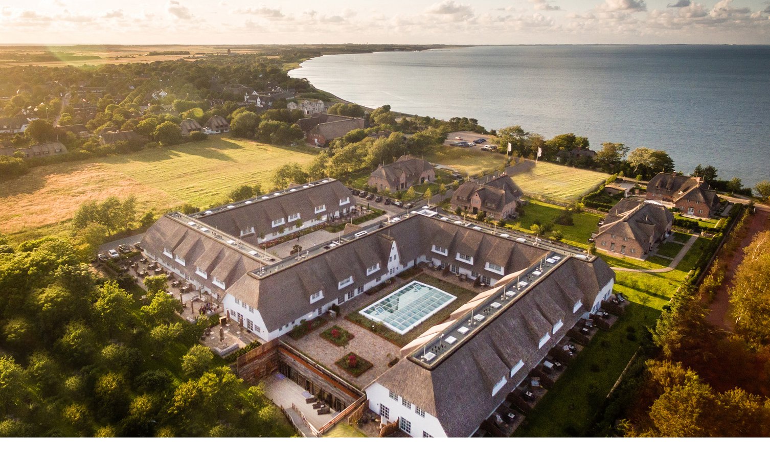 Luftaufnahme des Hotelgebäudes des Severin*s Resort und Spa sowie Blick auf die Küste Sylts