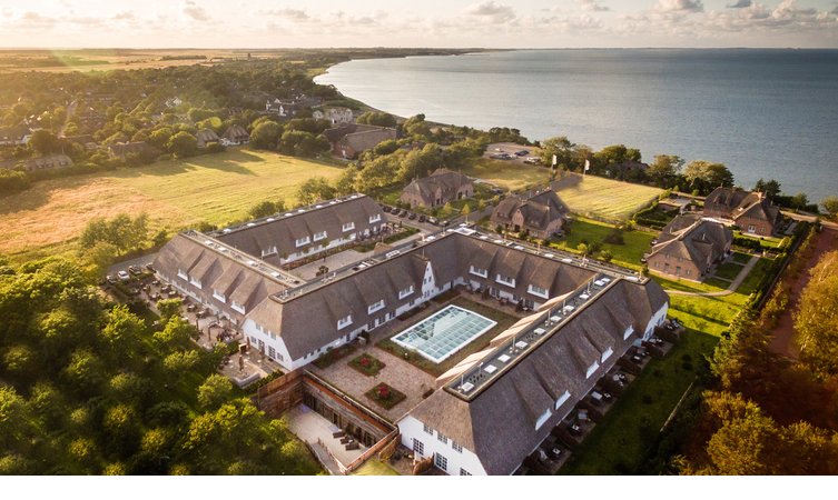 Luftaufnahme des Hotelgebäudes des Severin*s Resort und Spa sowie Blick auf die Küste Sylts Luftaufnahme des Severin*s Resort & Spa auf Sylt, umgeben von Natur mit Blick auf die Küste.